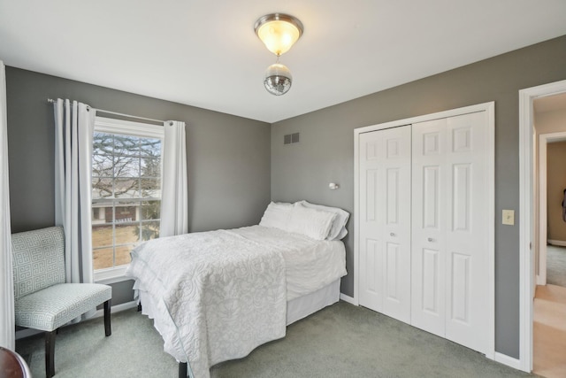 carpeted bedroom featuring baseboards, visible vents, and a closet