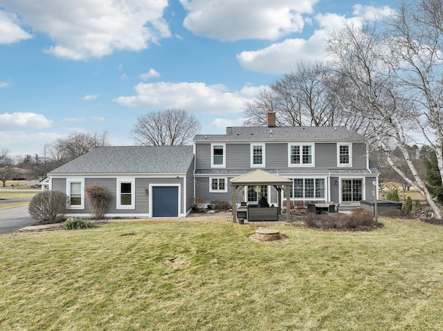 back of property with a gazebo, a yard, and an attached garage