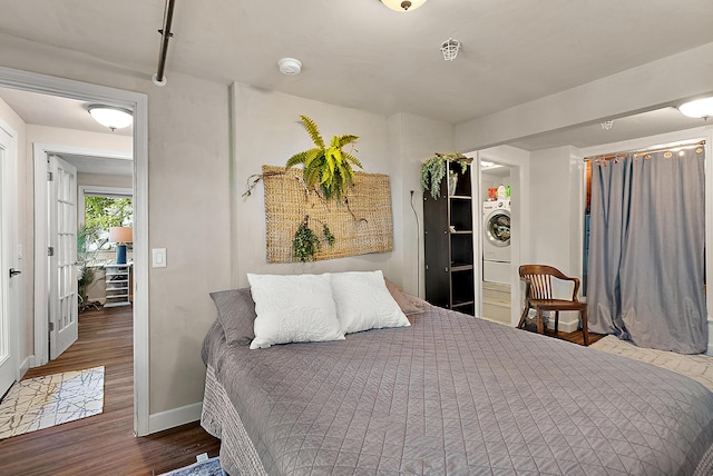 bedroom with washer / dryer, baseboards, and wood finished floors