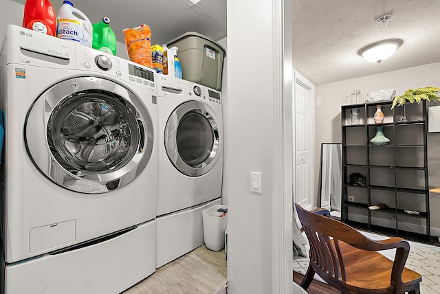 clothes washing area with washer and clothes dryer and wood finished floors