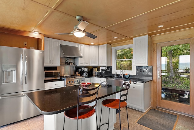 kitchen featuring exhaust hood, white cabinetry, appliances with stainless steel finishes, backsplash, and dark countertops