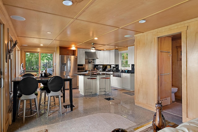 kitchen featuring dark countertops, granite finish floor, appliances with stainless steel finishes, white cabinets, and ventilation hood