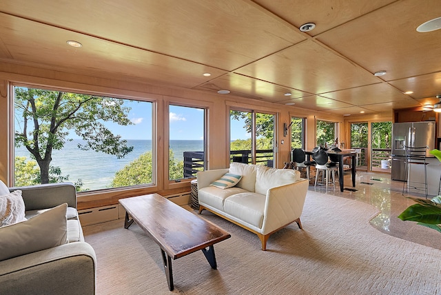 living area featuring a water view, a baseboard heating unit, and recessed lighting