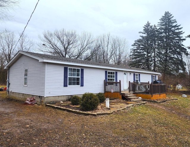 manufactured / mobile home featuring a shingled roof and a wooden deck