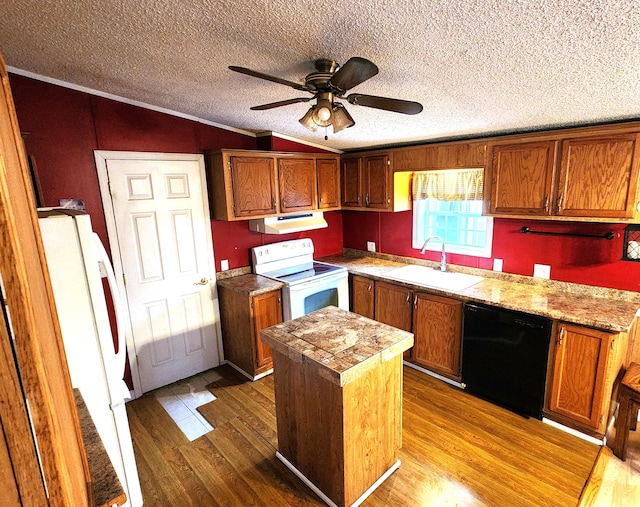 kitchen featuring white appliances, wood finished floors, vaulted ceiling, under cabinet range hood, and a sink