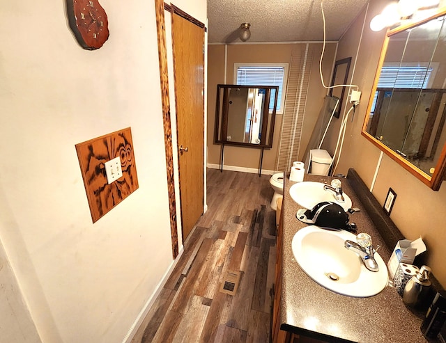 bathroom featuring a textured ceiling, toilet, wood finished floors, vanity, and baseboards