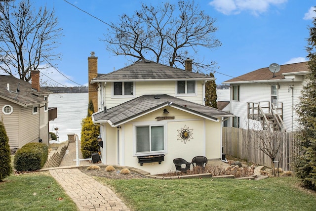 back of house featuring a yard, a chimney, and fence