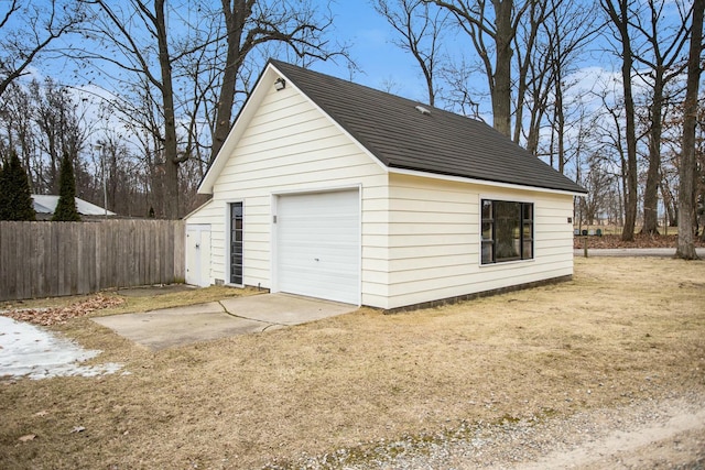 detached garage featuring fence and concrete driveway