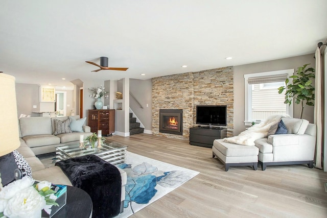 living room featuring recessed lighting, a fireplace, light wood-style flooring, and stairs