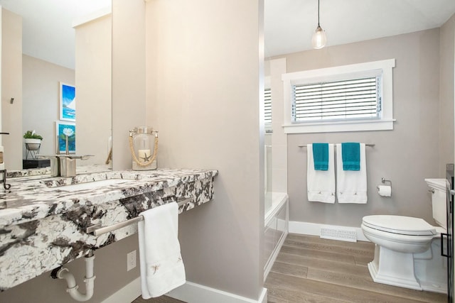 bathroom with toilet, wood finished floors, visible vents, and baseboards