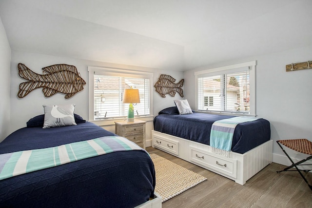 bedroom with light wood-style flooring, multiple windows, baseboards, and vaulted ceiling