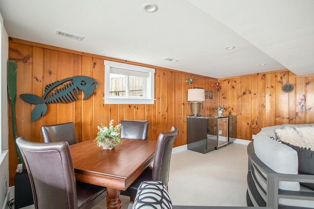 dining area with light floors, wooden walls, visible vents, and recessed lighting