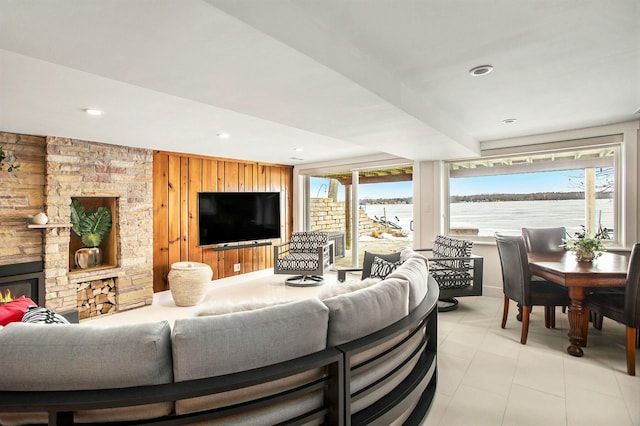 living area featuring a stone fireplace, wood walls, recessed lighting, and a healthy amount of sunlight