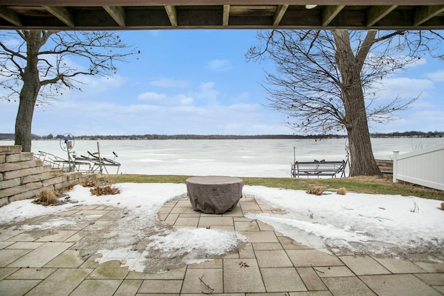 view of patio featuring a water view and fence