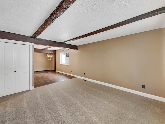 interior space featuring beam ceiling, a textured ceiling, and baseboards