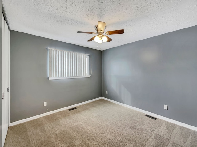 carpeted empty room featuring ceiling fan, visible vents, baseboards, and a textured ceiling