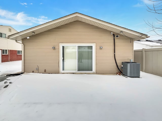 snow covered house with cooling unit and fence