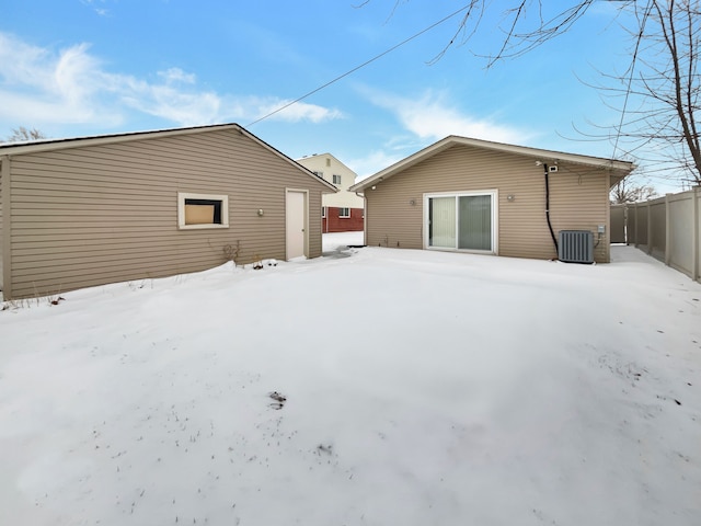 snow covered back of property featuring fence and central AC unit