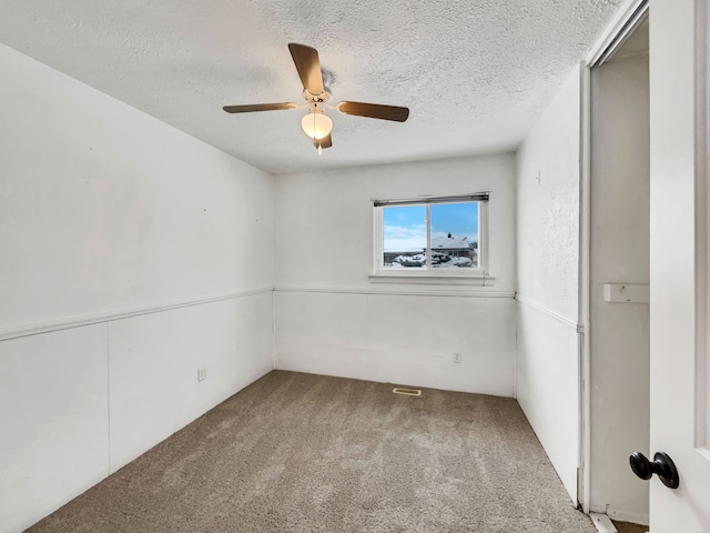 carpeted empty room featuring a ceiling fan and a textured ceiling