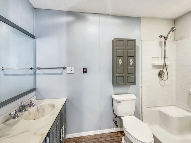 bathroom featuring toilet, vanity, wood finished floors, baseboards, and walk in shower