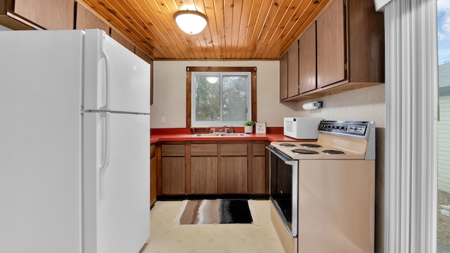 kitchen with white appliances, wooden ceiling, brown cabinets, light floors, and a sink