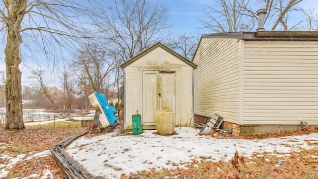 snow covered structure featuring a shed, fence, and an outdoor structure