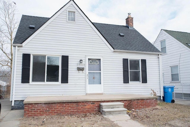 view of front facade with roof with shingles and a chimney