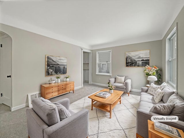 living area featuring light carpet, baseboards, visible vents, and arched walkways