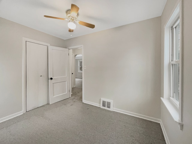 unfurnished bedroom with baseboards, visible vents, arched walkways, and carpet flooring