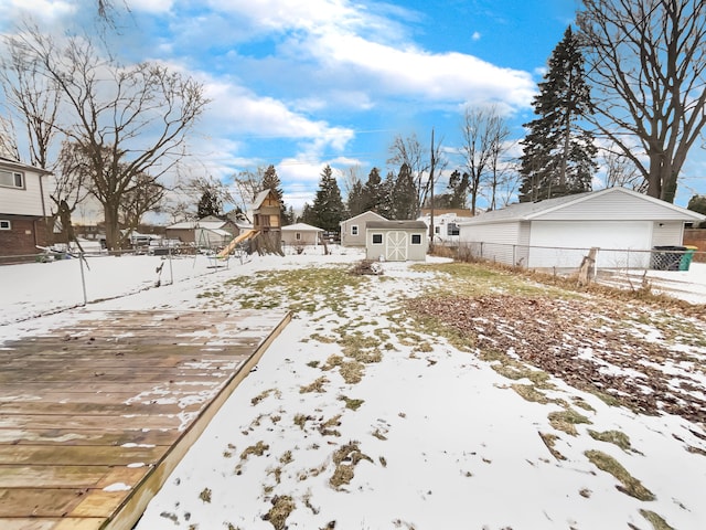 yard layered in snow featuring an outbuilding, fence, a shed, a garage, and a residential view