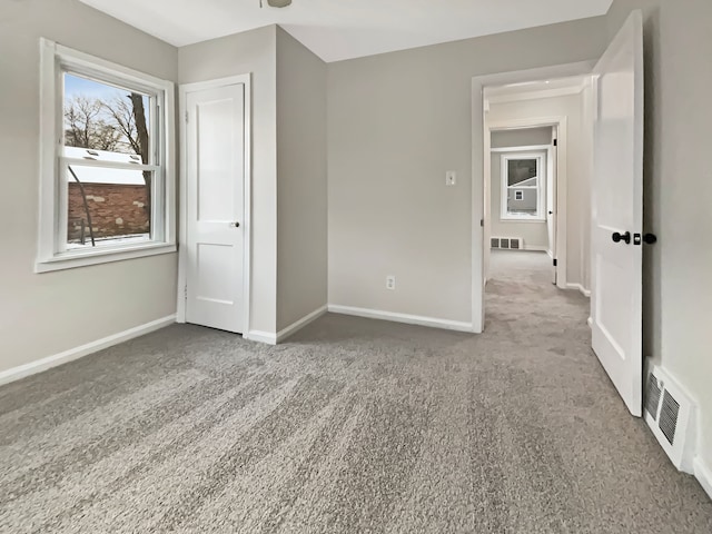 unfurnished bedroom featuring carpet floors, baseboards, and visible vents