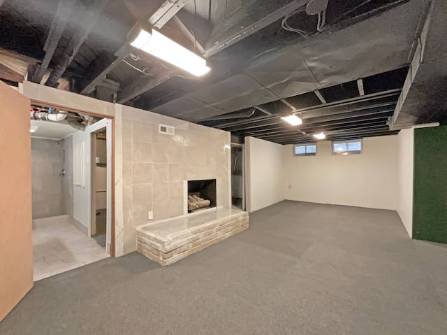 below grade area featuring visible vents and a fireplace with raised hearth