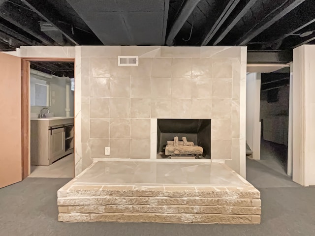 interior space with a sink, visible vents, concrete flooring, and a tiled fireplace