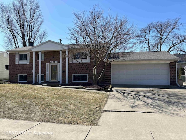 split foyer home with brick siding, driveway, an attached garage, and a front lawn