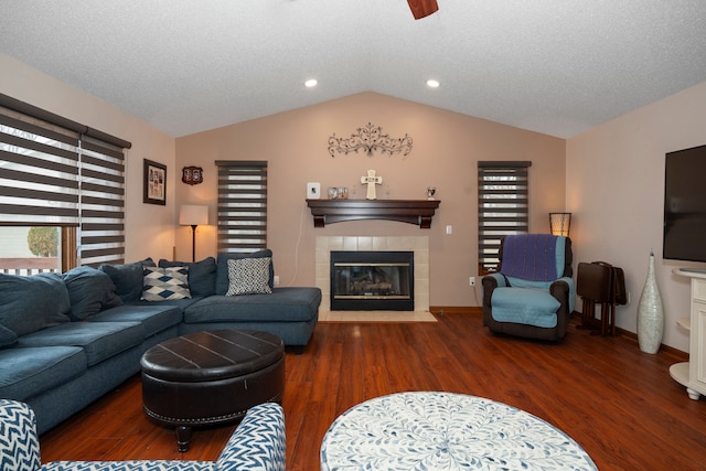 living area with vaulted ceiling, a fireplace, a textured ceiling, and wood finished floors