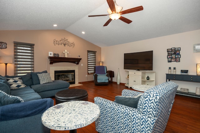 living area with vaulted ceiling, a tile fireplace, wood finished floors, and a ceiling fan