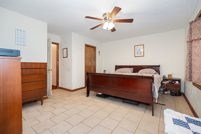 bedroom with light tile patterned floors, ceiling fan, baseboards, and a textured ceiling