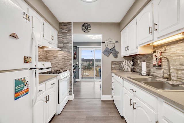 kitchen with white appliances, backsplash, a sink, and wood finished floors