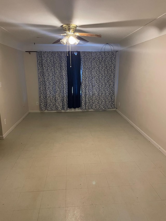 unfurnished room featuring ceiling fan and baseboards