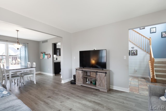 living room with baseboards, stairs, visible vents, and wood finished floors