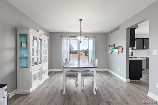 dining room with light wood-style flooring, visible vents, and baseboards