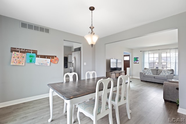 dining area with baseboards, visible vents, and wood finished floors