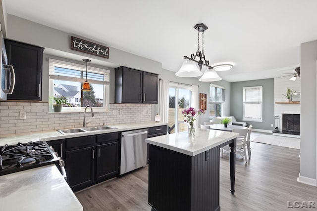 kitchen featuring a sink, open floor plan, decorative backsplash, dishwasher, and light wood finished floors