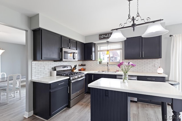 kitchen featuring stainless steel appliances, light countertops, a sink, and backsplash