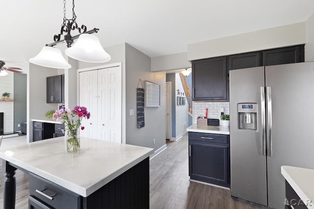 kitchen with ceiling fan, light countertops, hanging light fixtures, dark wood-style floors, and stainless steel fridge