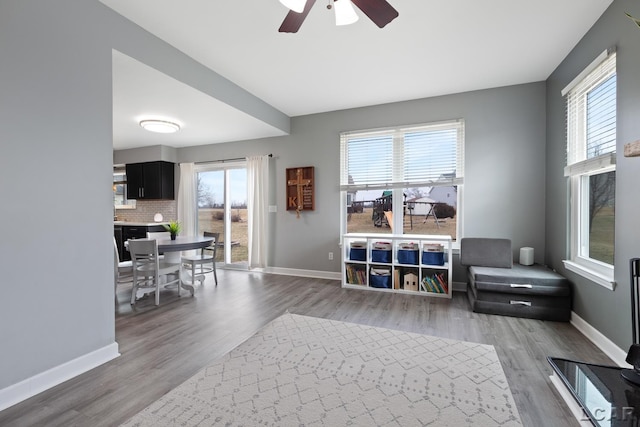 living area featuring ceiling fan, baseboards, and wood finished floors