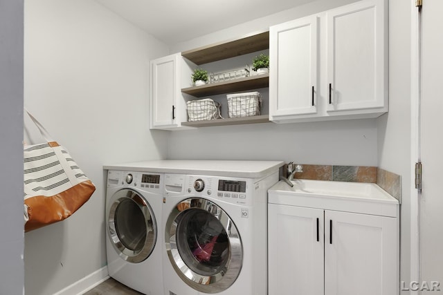 clothes washing area featuring washer and dryer, cabinet space, a sink, and baseboards