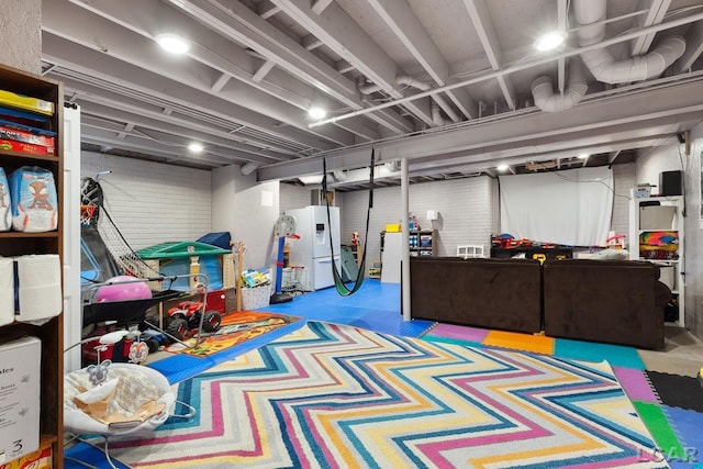 finished basement with white refrigerator with ice dispenser