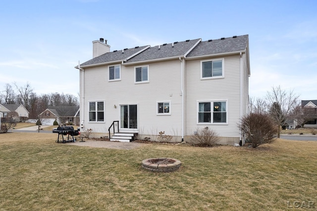 rear view of property featuring entry steps, a chimney, a patio, and a yard