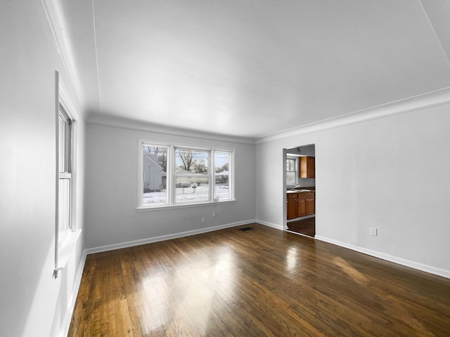 spare room featuring dark wood-type flooring, visible vents, and baseboards